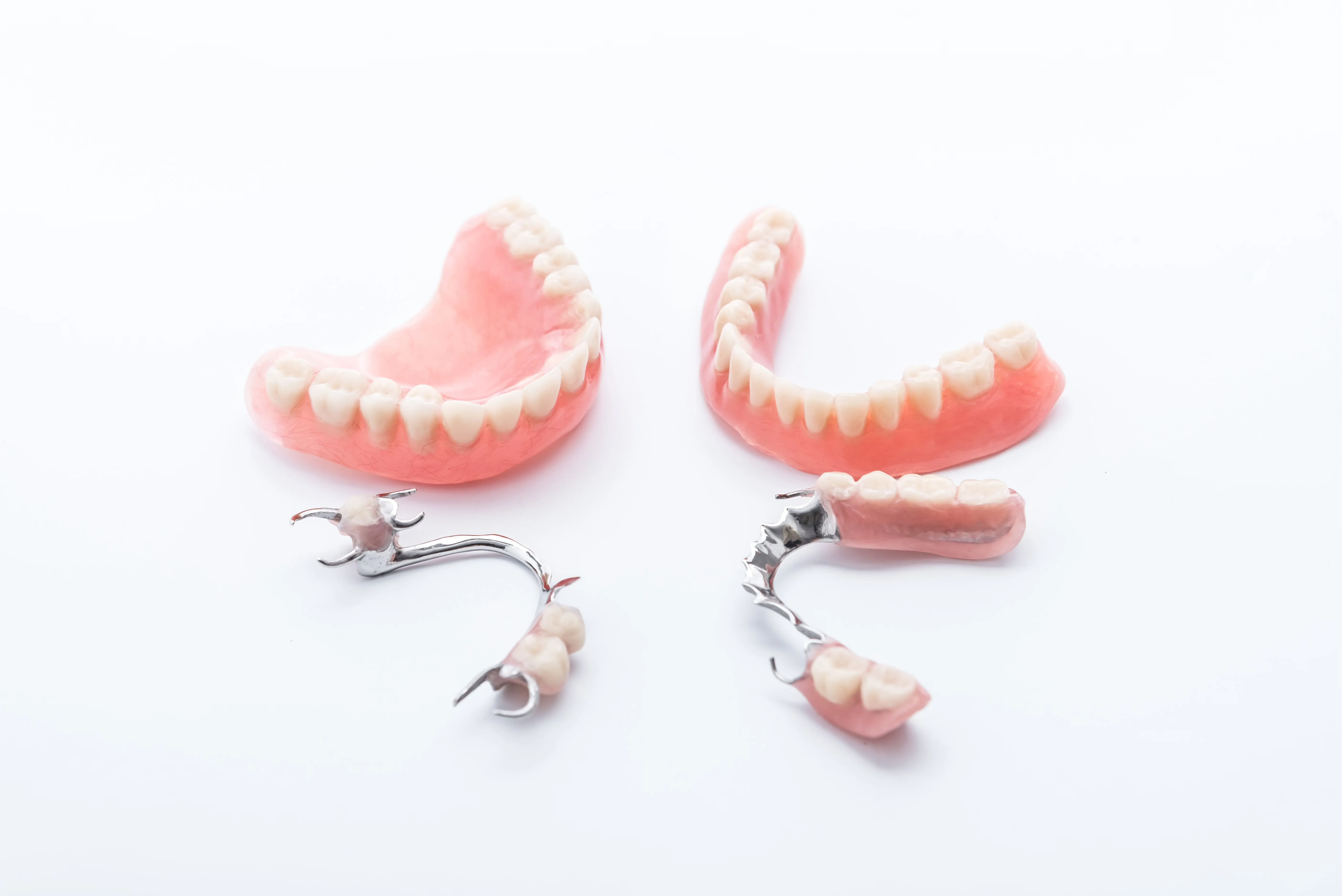 Complete and partial dentures on a white surface